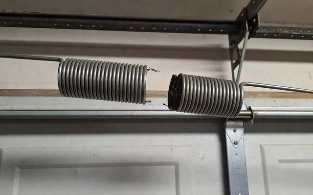 A broken torsion spring above a garage door